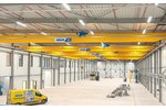 Een industriële hal met meerdere loopkranen op een baan, op de voorgrond een ABUS-servicevoertuig.