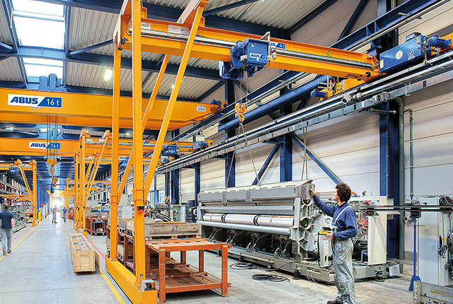 ABUS-halfportaalkraan in een industriële hal met een draagvermogen tot 10 ton en een overspanning tot 15 meter voor flexibele materiaalverplaatsing op werkplekken.
