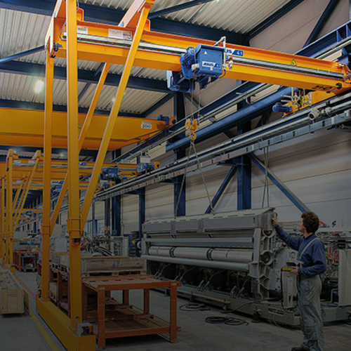 ABUS-halfportaalkraan in een industriële hal met een draagvermogen tot 10 ton en een overspanning tot 15 meter voor flexibele materiaalverplaatsing op werkplekken.