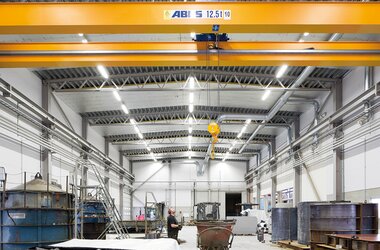 Moderne industriële hal met een ABUS-loopkraan (12,5 t) en hijshaken voor efficiënt materiaaltransport in de productieruimte.